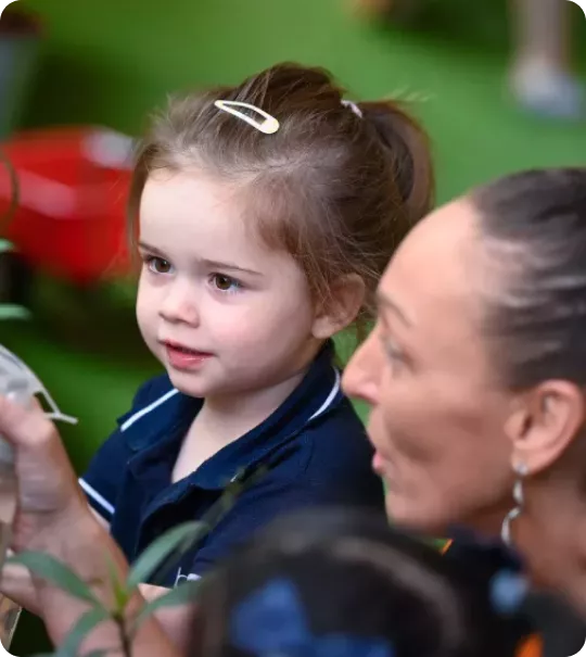 Nursery teacher engaging preschooler in nature-based learning activity aligned with UAE education vision.