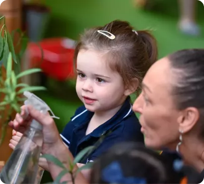 Nursery teacher engaging preschooler in nature-based learning activity aligned with UAE education vision. 
