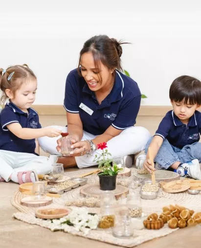 Happy toddler laughing during a sensory play activity at a British nursery in the UAE.